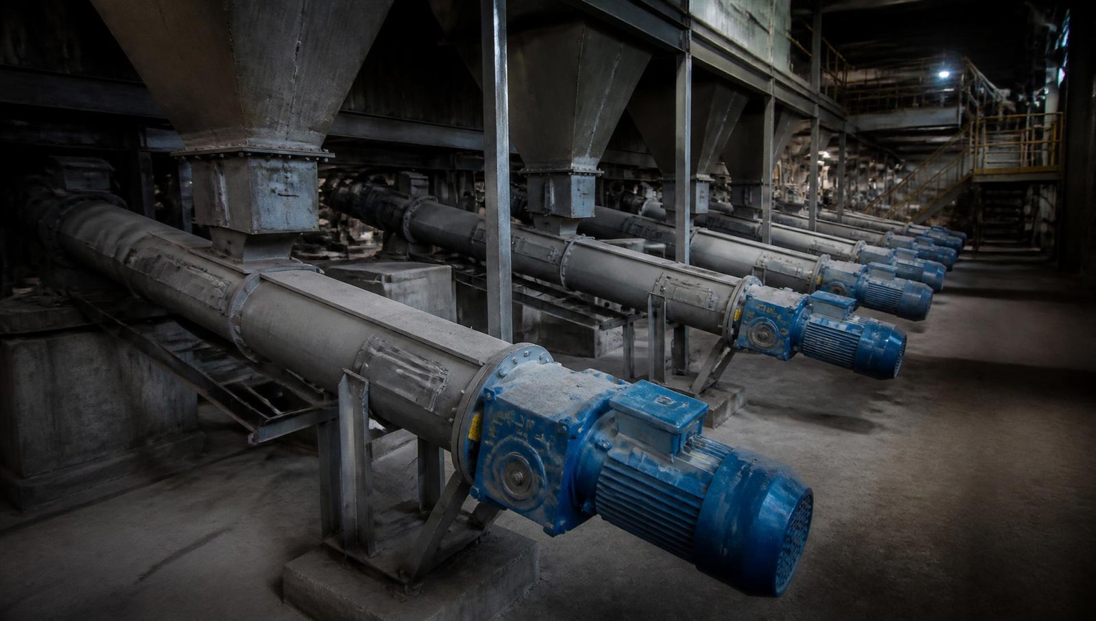 Industrial screw conveyors with geared motor drives installed in a bulk material handling plant